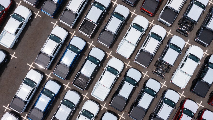 An overhead view of a large number of pickup trucks in a dealership lot.