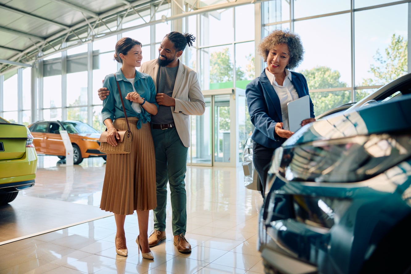 A salesperson showing off a vehicle to a couple inside a dealership.