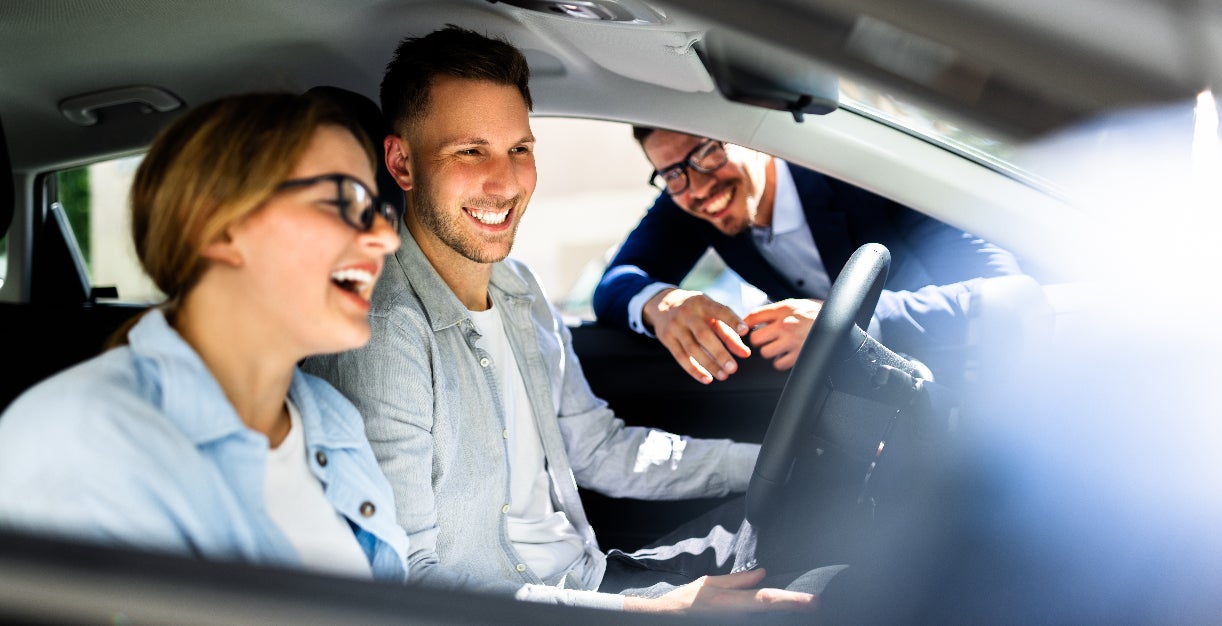 Representative showing a young couple a used Dodge model